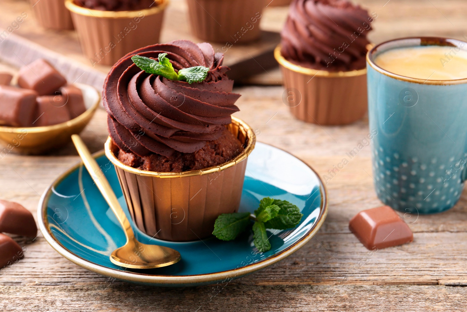 Photo of Delicious cupcakes with chocolate pieces and mint on wooden table