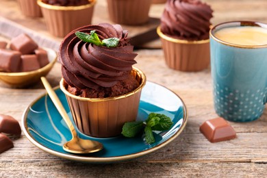 Photo of Delicious cupcakes with chocolate pieces and mint on wooden table