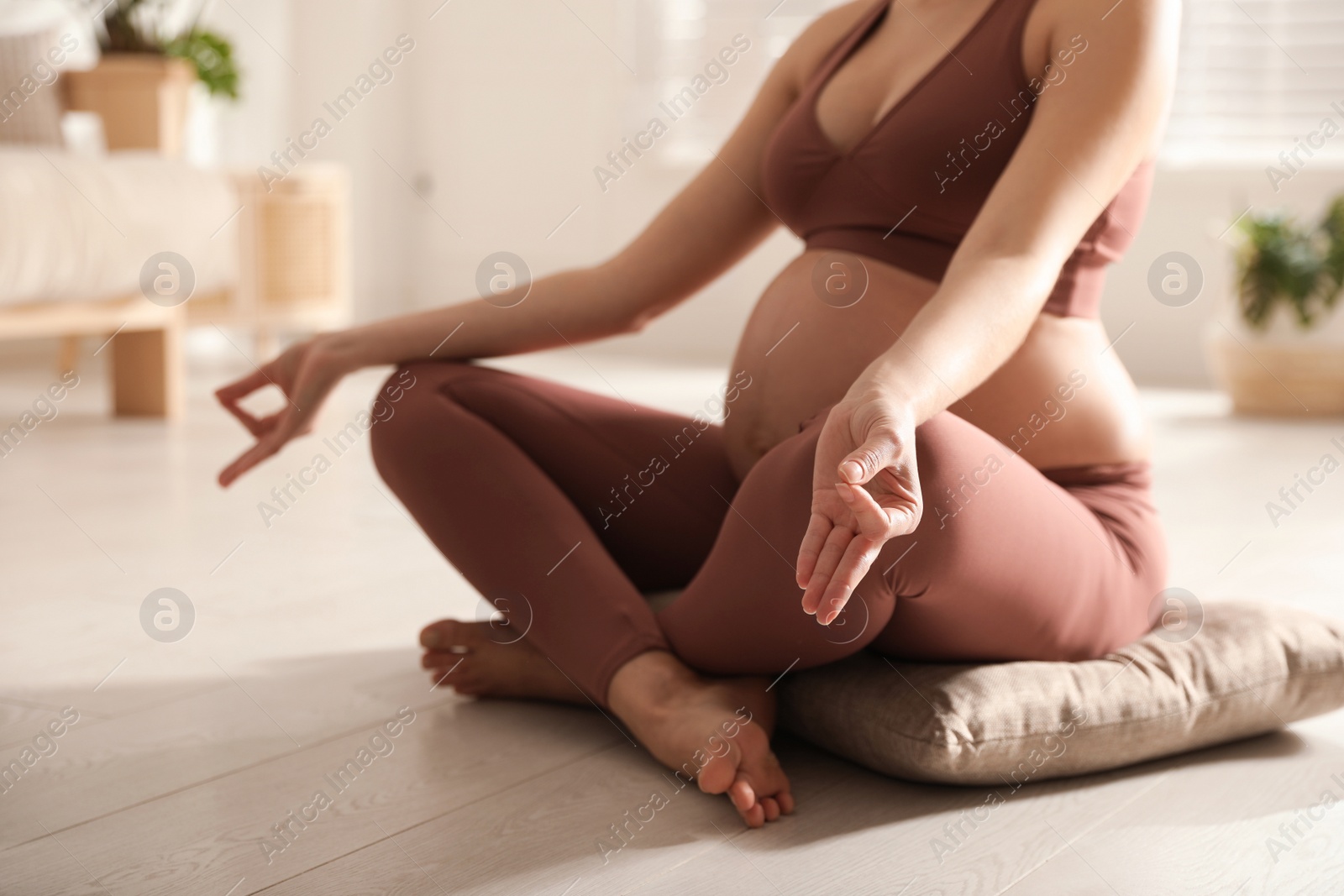 Photo of Young pregnant woman practicing yoga at home, closeup