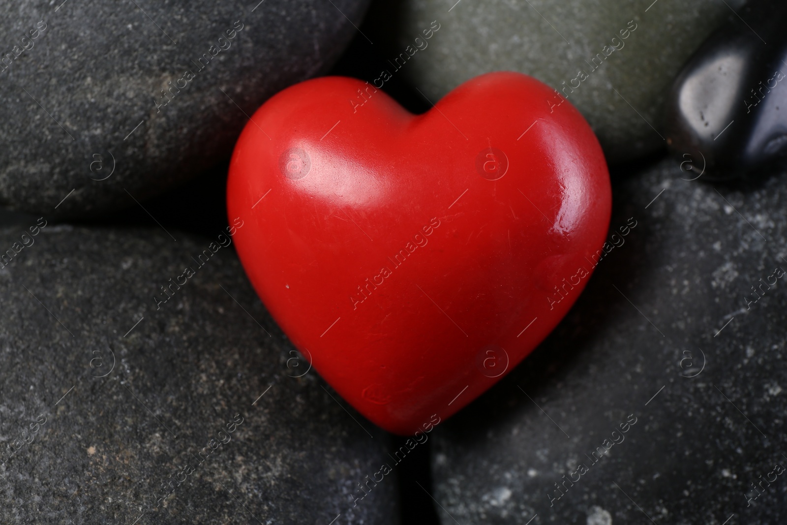 Photo of Red decorative heart on pebble stones, above view