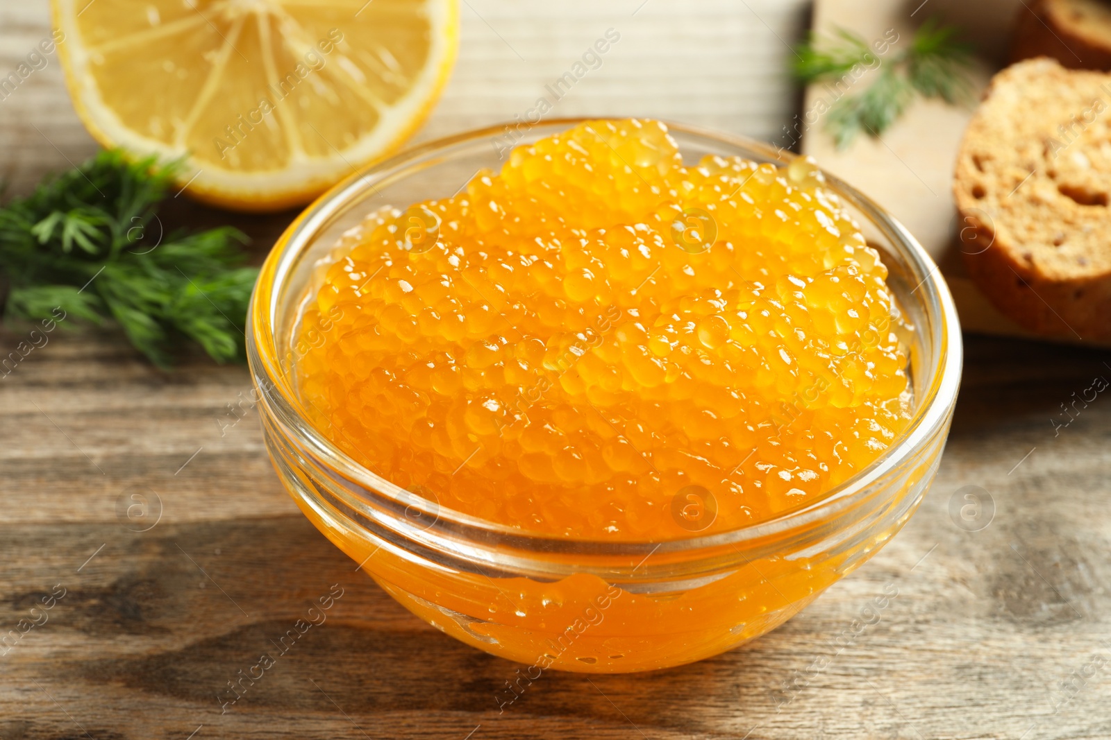 Photo of Fresh pike caviar in bowl on wooden table, closeup