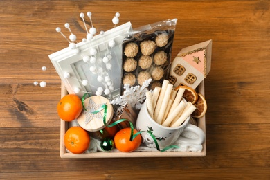 Photo of Crate with gift set and Christmas decor on wooden table, top view