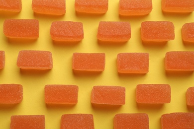 Tasty orange jelly candies on yellow background, flat lay