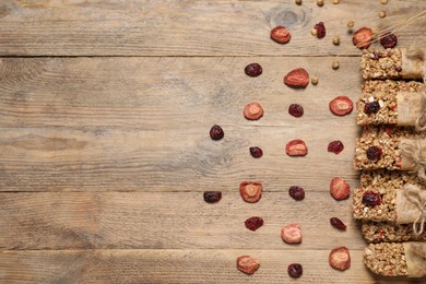 Tasty granola bars on wooden table, flat lay. Space for text