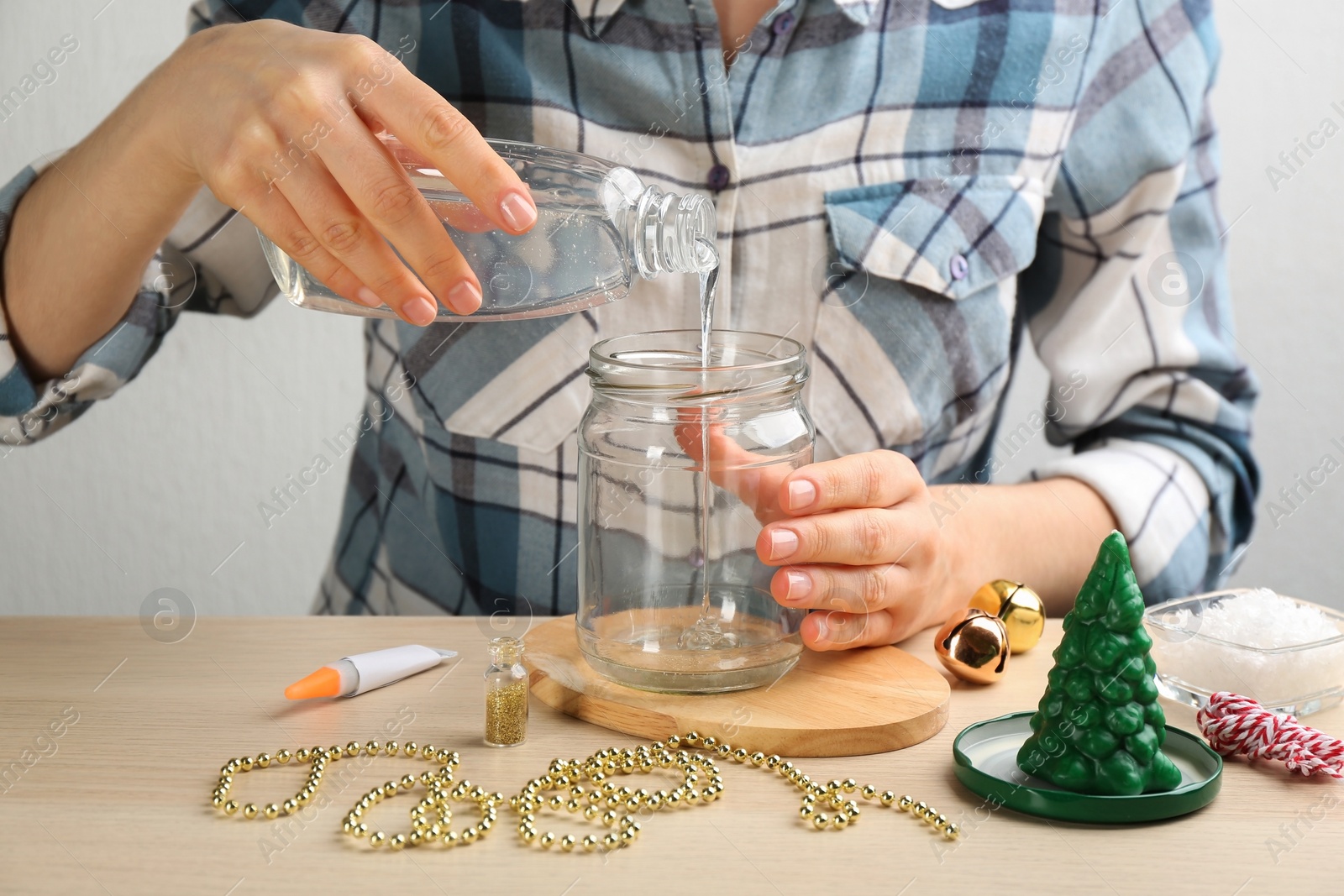 Photo of Woman making beautiful snow globe at wooden table, closeup