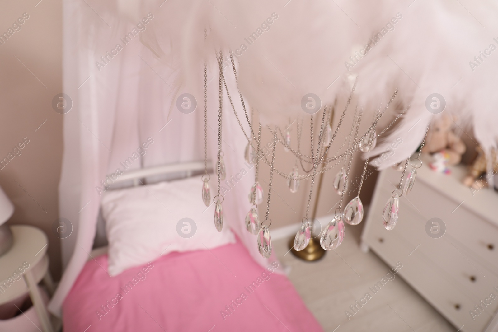 Photo of Beautiful decorative cloud with crystals hanging over bed in child's room. Interior design