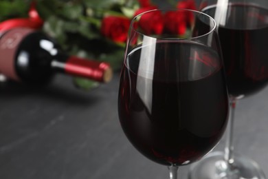 Photo of Glasses of red wine on black table, closeup. Space for text