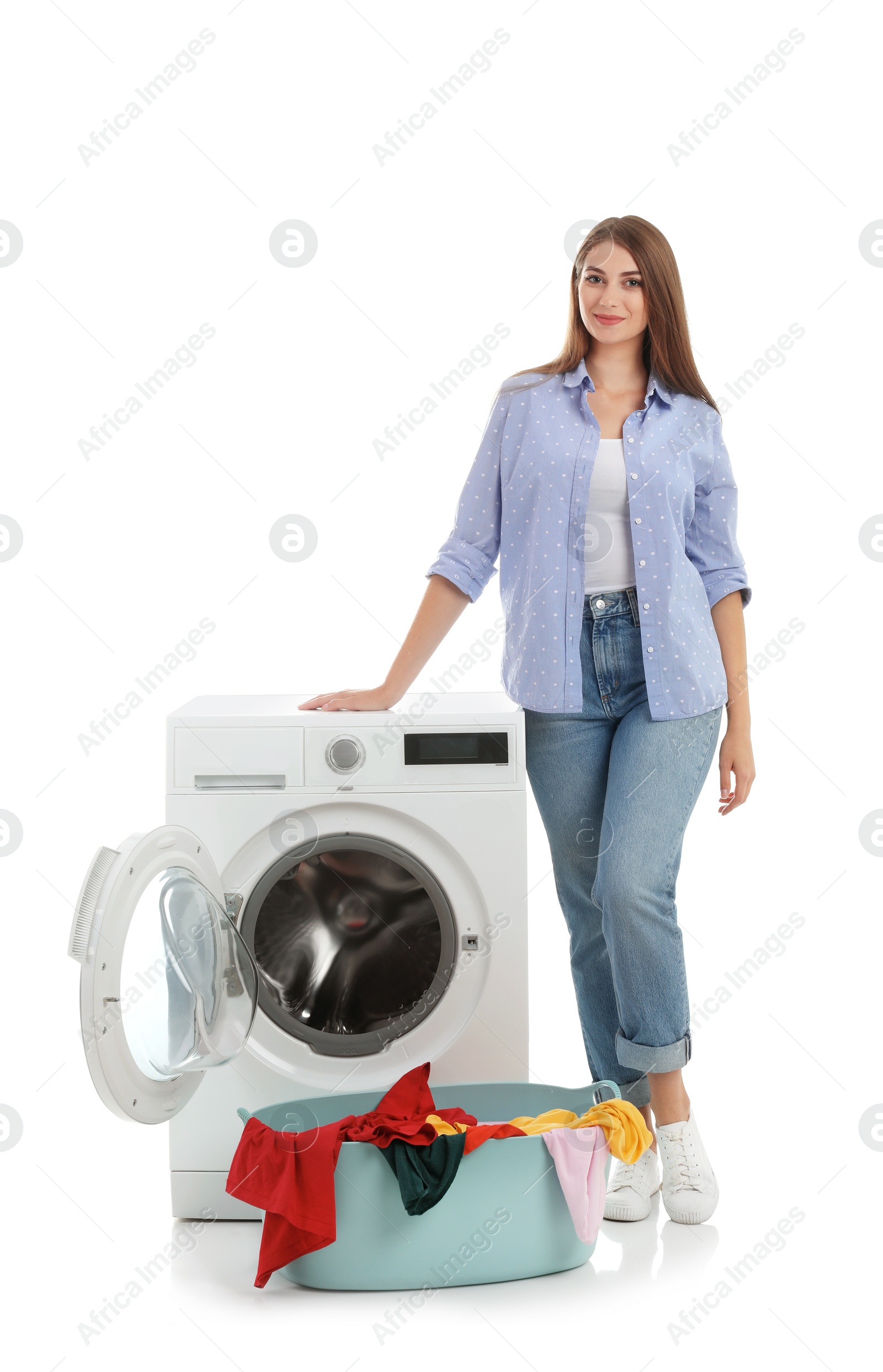 Photo of Young woman near washing machine and basket with laundry on white background