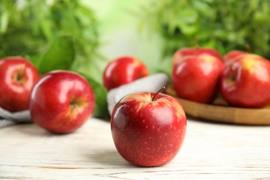 Photo of Ripe juicy red apples on white wooden table against blurred background. Space for text