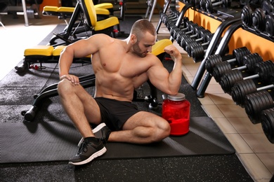 Portrait of athletic man with protein shake powder in gym