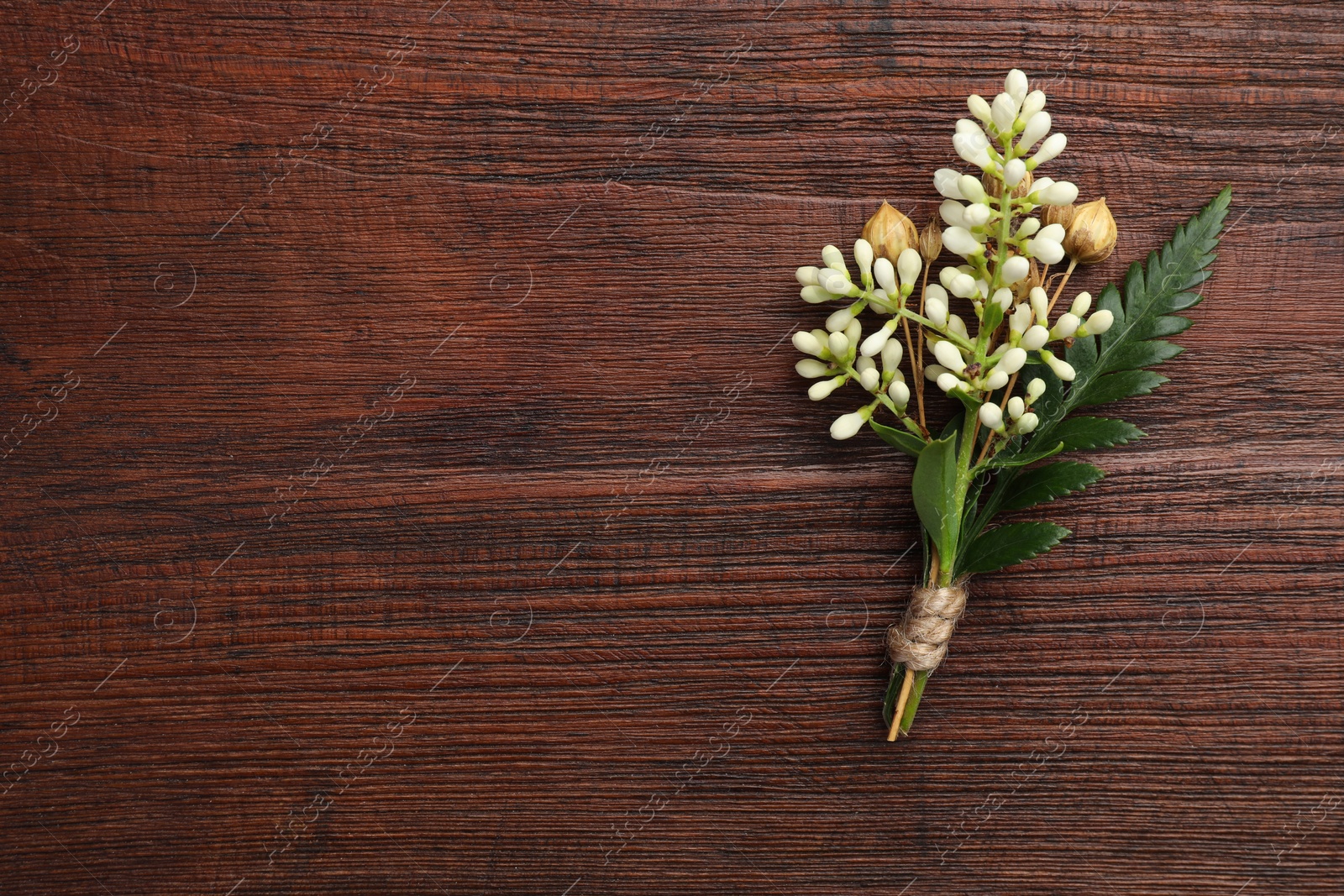 Photo of Small stylish boutonniere on wooden table, top view. Space for text