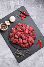 Photo of Pieces of raw beef meat, products and spices on grey textured table, top view