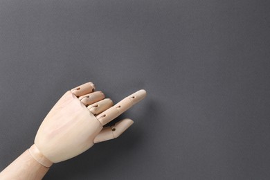 Wooden mannequin hand on grey background, top view. Space for text