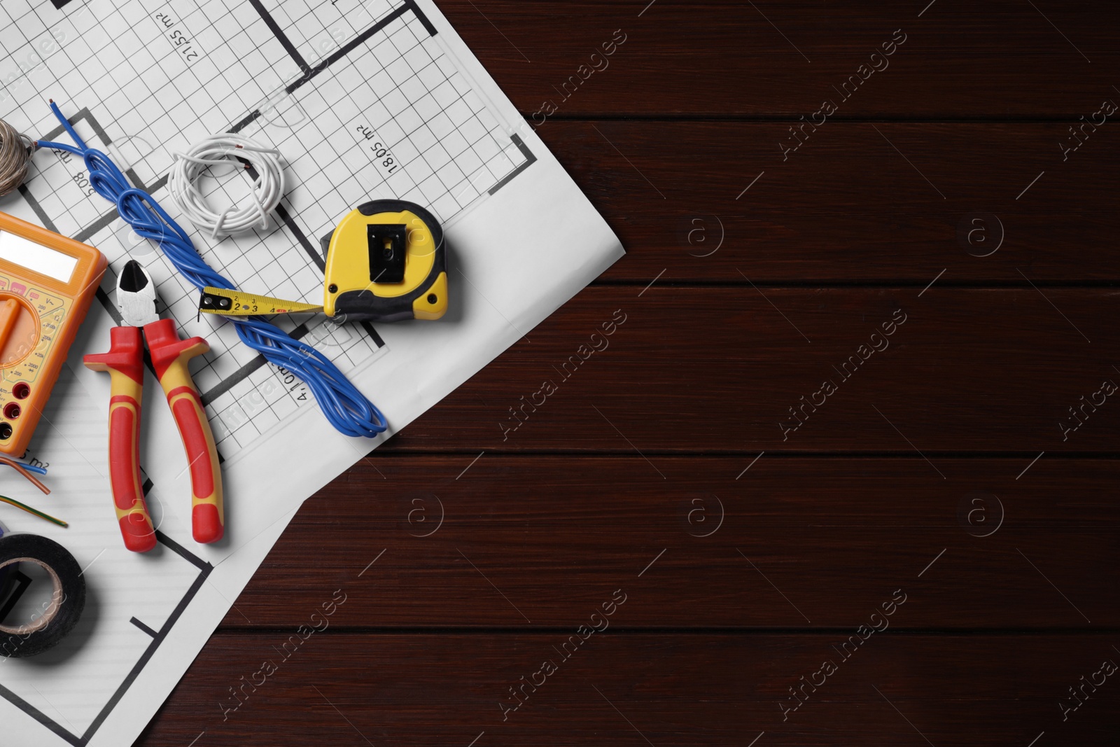 Photo of Different wires and electrician's tools on wooden table, top view. Space for text