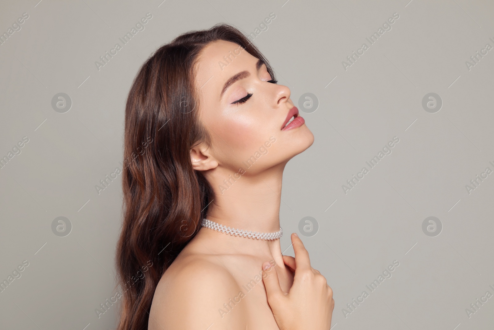 Photo of Young woman wearing elegant pearl necklace on grey background, space for text