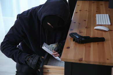 Dangerous masked criminal stealing money from house