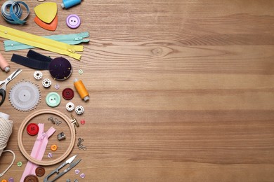 Flat lay composition with different sewing accessories on wooden background. Space for text