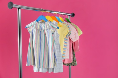 Photo of Rack with stylish children clothes on pink background. Space for text