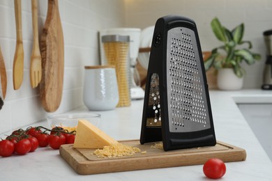 Photo of Grater, cheese and cherry tomatoes on kitchen counter
