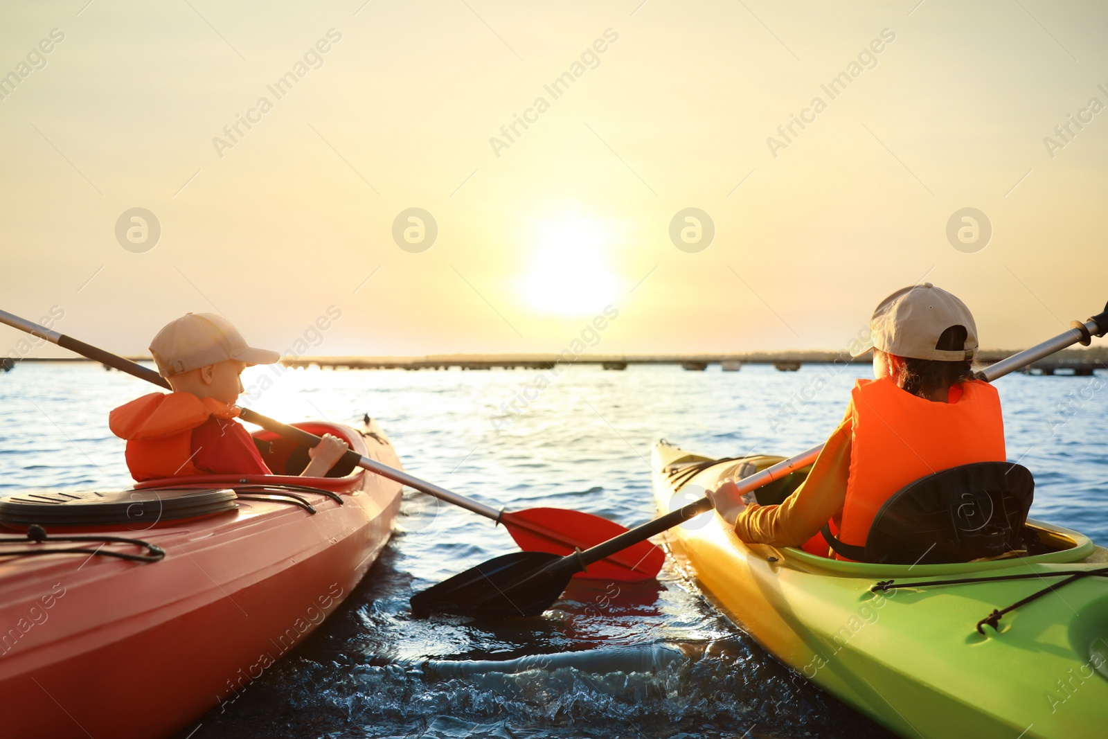 Photo of Little children kayaking on river, back view. Summer camp activity