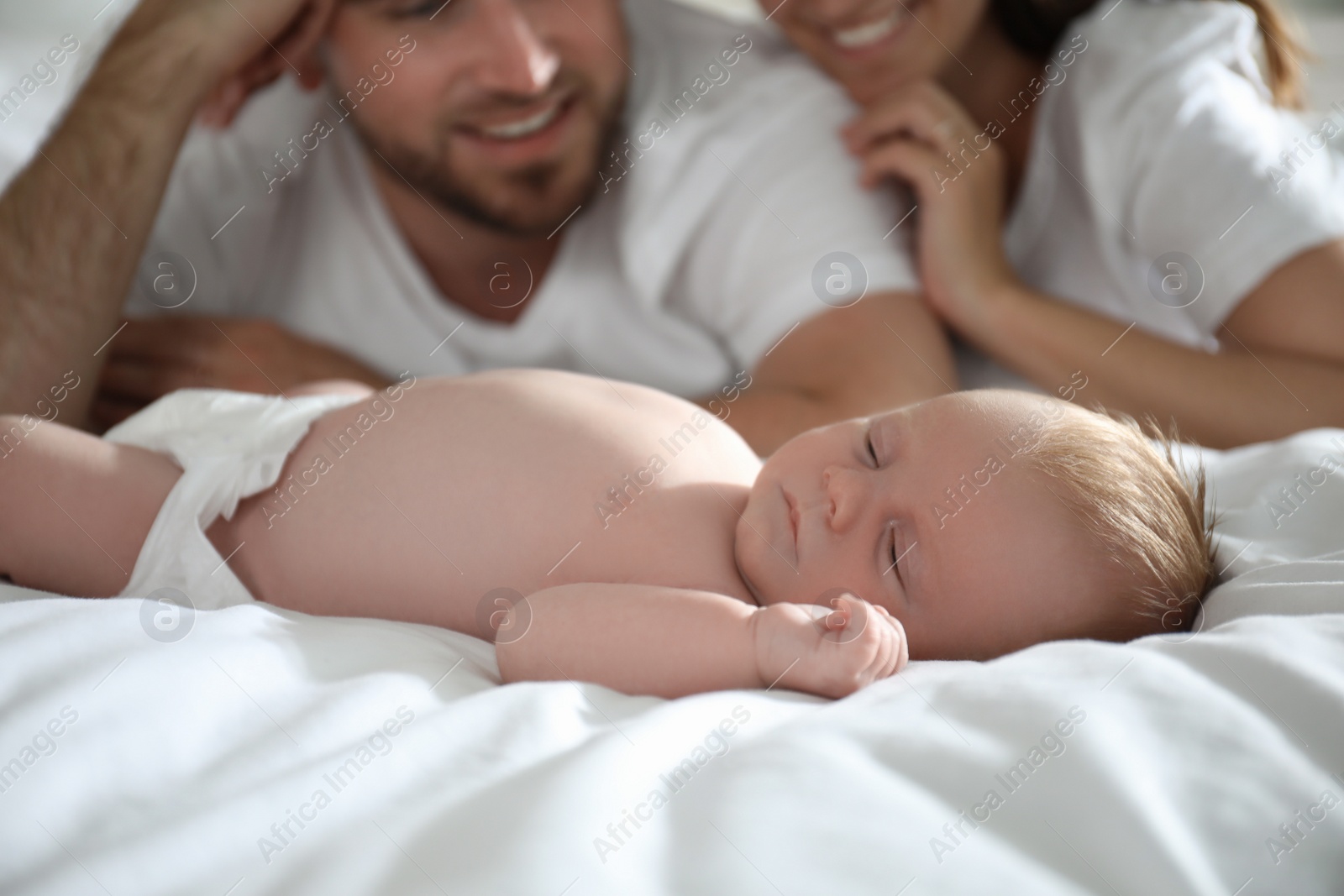 Photo of Happy couple with their newborn baby on bed, closeup