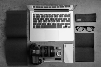 Photo of Flat lay composition with laptop, camera and smartphone on grey stone table. Designer's workplace