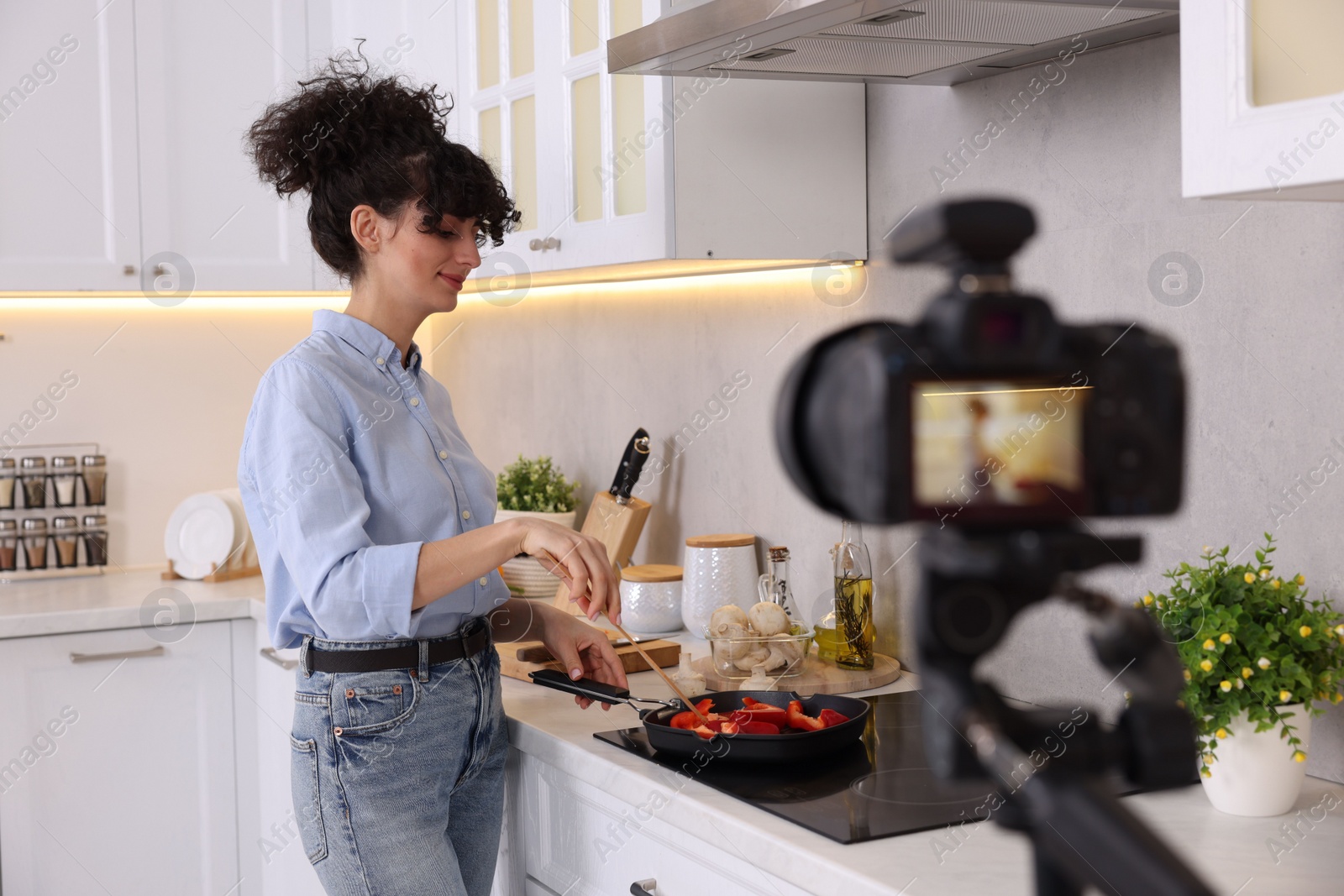 Photo of Food blogger cooking while recording video in kitchen