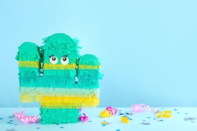 Photo of Cactus shaped pinata and decor on light blue background. Space for text