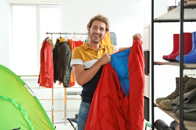 Photo of Young man choosing sleeping bag in store