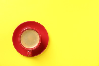 Tasty coffee in cup on yellow background, top view. Space for text