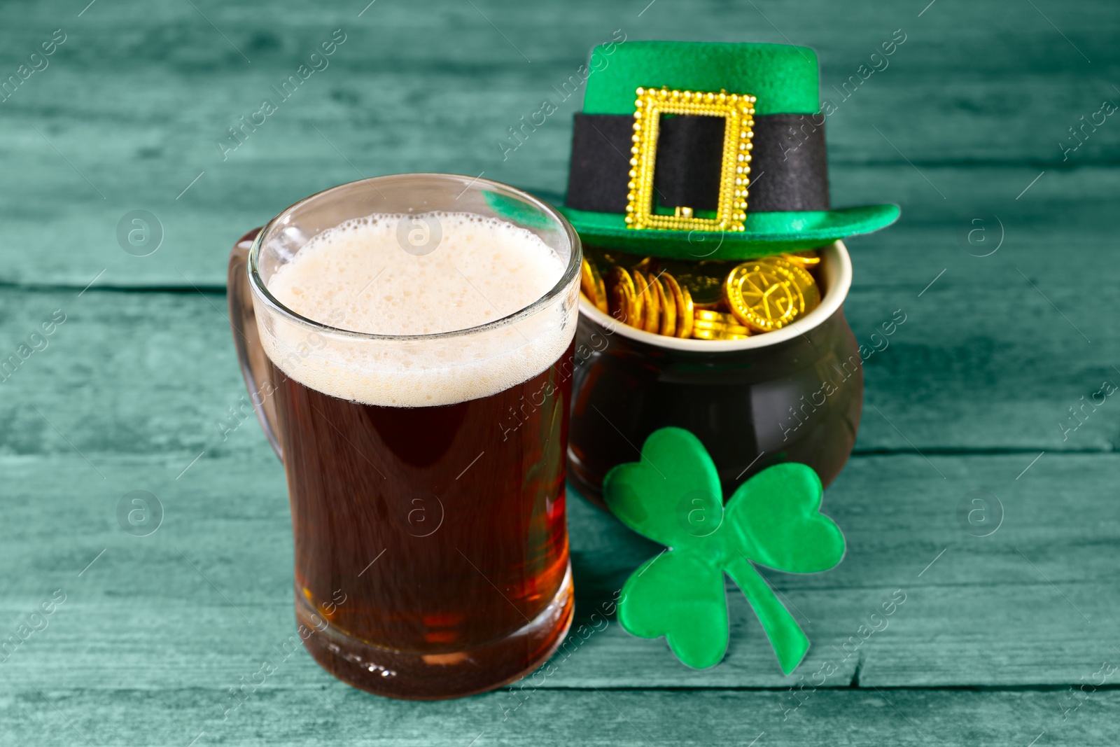 Image of St. Patrick's day. Beer, leprechaun hat, pot of gold and decorative clover leaf on green wooden table