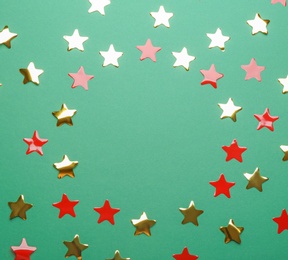 Photo of Frame made of confetti stars with space for text on green background, top view. Christmas celebration