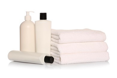 Folded soft terry towels with cosmetic products on white background