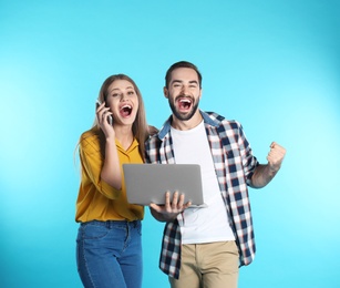 Photo of Emotional young people with laptop celebrating victory on color background