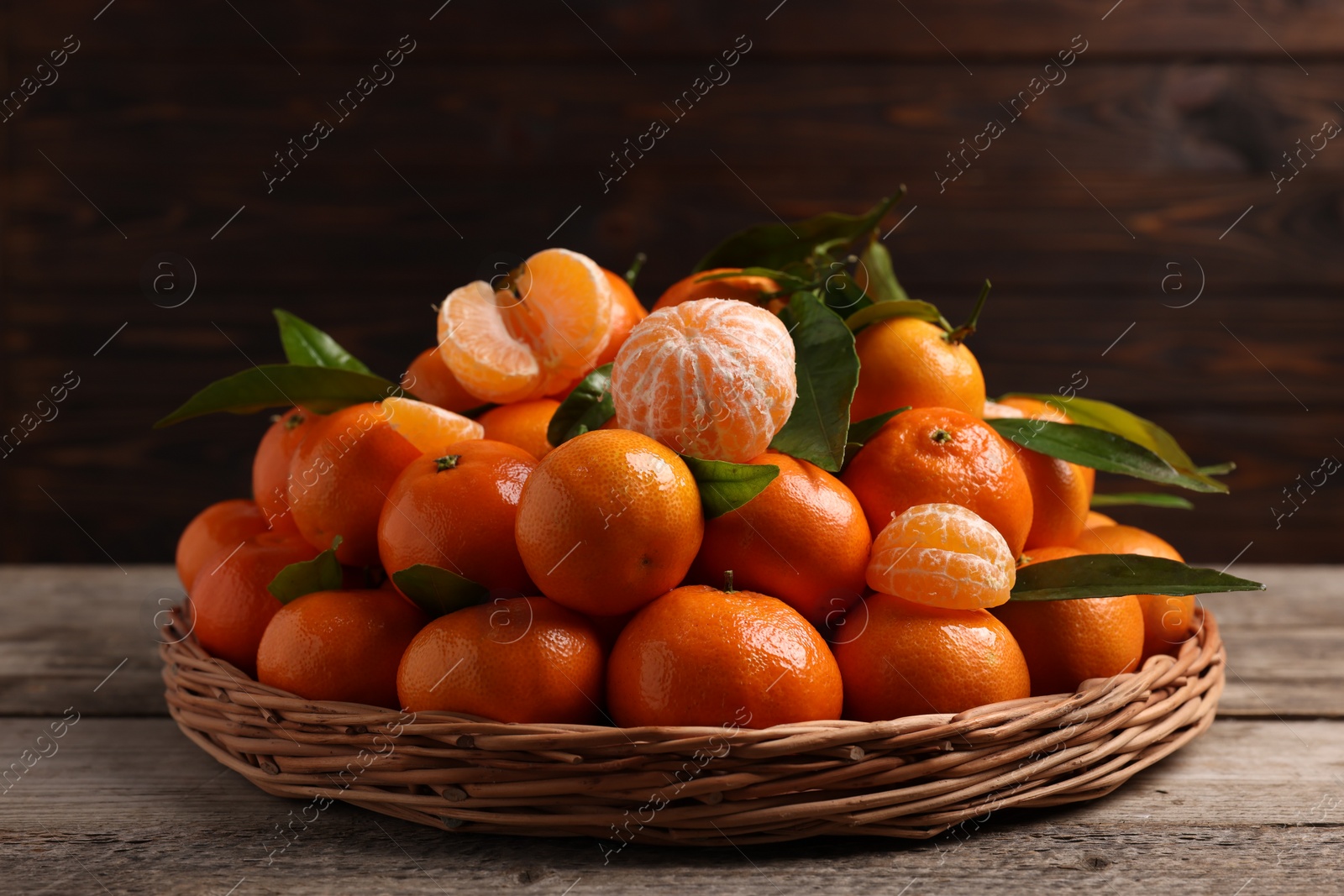 Photo of Fresh ripe juicy tangerines and green leaves on wooden table