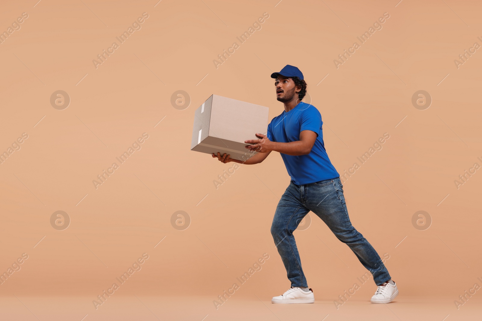 Photo of Courier running to deliver parcel on light brown background, space for text