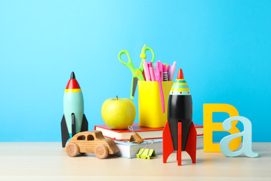 Bright toy rockets, car and school supplies on wooden table