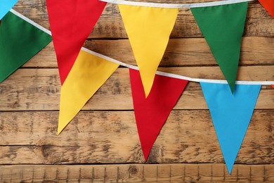 Buntings with colorful triangular flags hanging on wooden wall. Festive decor