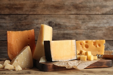 Different types of delicious cheese on table against wooden background