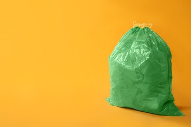 Photo of Trash bag full of garbage on yellow background. Space for text