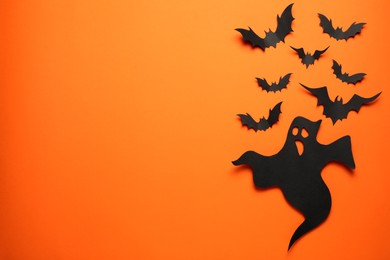 Photo of Flat lay composition with paper ghost and bats on orange background, space for text. Halloween celebration