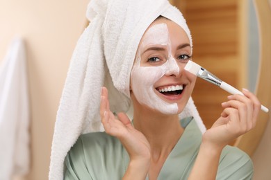 Photo of Woman applying face mask indoors. Spa treatments