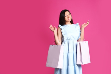 Photo of Beautiful young woman with blank paper bags against color background, space for text