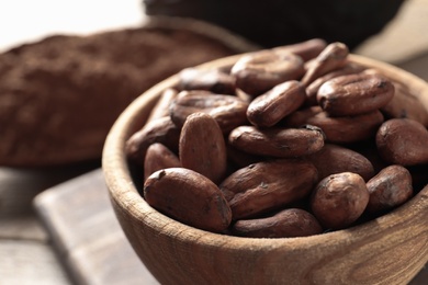 Photo of Wooden bowl with cocoa beans on table, closeup