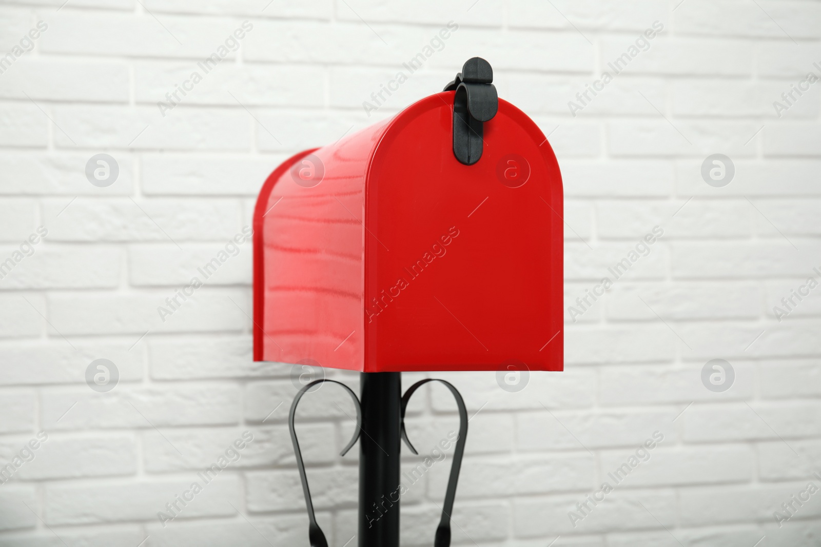 Photo of Closed red letter box near white brick wall