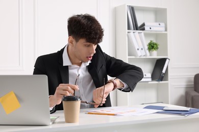 Emotional young man working at table in office. Deadline concept