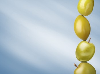 Image of Stack of whole green olives on pastel light blue gradient background, space for text