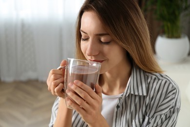 Young woman drinking chocolate milk in room