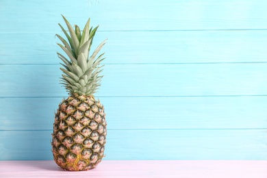 Photo of Fresh pineapple on table against color wall