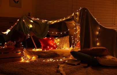 Beautiful play tent decorated with festive lights at home